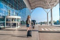 Adult woman tourist with hand luggage suitcase and backpack goes to the airport for journey. Woman ready to board the Royalty Free Stock Photo