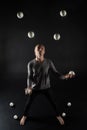 Blonde hair juggler with white balls on black background