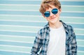 Blonde hair 12 year old caucasian teenager boy Fashion portrait dressed white t-shirt with checkered shirt in blue sunglasses with