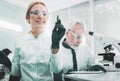 Blonde-haired biologist wearing glasses writing on glass board