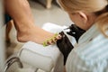 Blonde-haired chiropodist wearing uniform coloring nails of her client