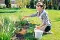 Blonde-haired family woman sitting on the grass near little hoe enriching soil Royalty Free Stock Photo