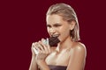 Blonde-haired model with bob cut needing much effort to bite chocolate