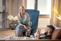 Blonde-haired psychoanalyst giving tea to client lying on sofa