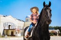 Blonde-haired teenage girl riding gentle black horse