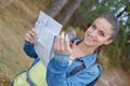 Blonde hiker with compass and reading map in nature