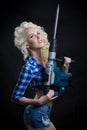 Blonde with industrial hammer. dark background.