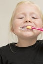 Blonde Kid Brushing Her Teeth with a Pink Toothbrush