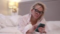 blonde lady is using smartphone in bed before sleep, chatting and sending message Royalty Free Stock Photo