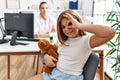 Blonde little girl at pediatrician clinic with female doctor smiling happy doing ok sign with hand on eye looking through fingers Royalty Free Stock Photo