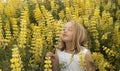 Blonde little girl smelling yellow wildflowers