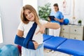 Blonde little girl wearing arm on sling at rehabilitation clinic smiling happy pointing with hand and finger Royalty Free Stock Photo