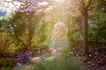 Blonde little toddler child with binoculars, sitting in garden on sunset Royalty Free Stock Photo