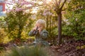 Blonde little toddler child with binoculars, sitting in garden on sunset Royalty Free Stock Photo