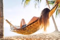 Blonde longhaired woman relaxing in hammock hinged between palm trees on the sand beach Royalty Free Stock Photo