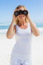 Blonde looking through binoculars on the beach Royalty Free Stock Photo