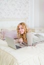 Blonde lying on her bed using laptop at home in the Royalty Free Stock Photo