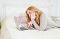 Blonde lying on her bed using laptop at home in the Royalty Free Stock Photo