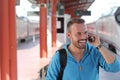 Blonde man calling by phone from train station Royalty Free Stock Photo
