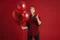 Blonde man pointing finger at camera while posing with balloons Royalty Free Stock Photo