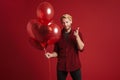 Blonde man pointing finger at camera while posing with balloons Royalty Free Stock Photo
