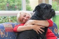 Blonde middle-aged woman is embracing the dog