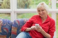 Blonde middle-aged woman is holding a cell phone