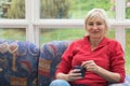 Blonde middle-aged woman is sitting on a sofa Royalty Free Stock Photo