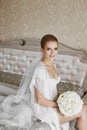 blonde model girl with blue eyes and gentle makeup, in lace peignoir and in white lingerie with the bouquet of Royalty Free Stock Photo