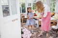 Blonde mom with her little laughing girl is watering peonies from a watering can in a summer house Royalty Free Stock Photo