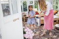 Blonde mom with her little laughing girl is watering peonies from a watering can in a summer house Royalty Free Stock Photo