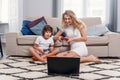 Blonde mother and her little funny son playing video games on console. Happy family time together. Royalty Free Stock Photo