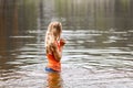 A blonde in an orange wet t-shirt stands waist-deep in water Royalty Free Stock Photo