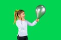 Blonde pensive kid with pigtails looks at a ultimate grey balloon. Green background. Children`s emotion concept