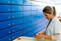 Blonde pharmacist checking a medical product and precription in one of the alphabetical pharmacy drawers