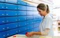 Blonde pharmacist checking a medical product and precription in one of the alphabetical pharmacy drawers