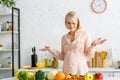 Blonde pregnant woman gesturing near fruits and vegetables