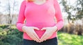 Blonde pregnant woman in pink shirt on a sunny spring day