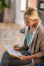 Blonde psychoanalyst wearing stylish cardigan making notes