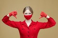 Blonde in red gloves and a mask points her thumb down. the concept of preventing coronavirus covid 19 Royalty Free Stock Photo