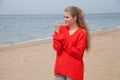 The blonde in the red walks along the beach of the sea coast Royalty Free Stock Photo