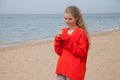 The blonde in the red walks along the beach of the sea coast Royalty Free Stock Photo