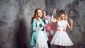 Blonde and redhead. Two young charming girlfriends at the party with balloons. On gray textured background Royalty Free Stock Photo