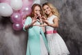 Blonde and redhead. Two young charming girlfriends at the party. Show sign heart. Focus on the hands Royalty Free Stock Photo