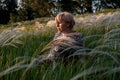 The blonde is resting in the field in the fluffy grass. Unity with nature, travel across the country. Recreation