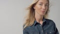 Blonde 30s woman alone in studio wears denim look