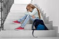 Blonde school girl sitting on stairs. Royalty Free Stock Photo