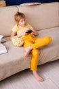 Blonde schoolboy boy plays video games, holds a gamepad, eats popcorn instead of learning lessons on blue background Royalty Free Stock Photo