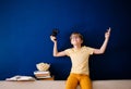 Blonde schoolboy boy plays video games, holds a gamepad, eats popcorn instead of learning lessons on blue background Royalty Free Stock Photo