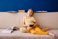 Blonde schoolboy boy plays video games, holds a gamepad, eats popcorn instead of learning lessons on blue background Royalty Free Stock Photo